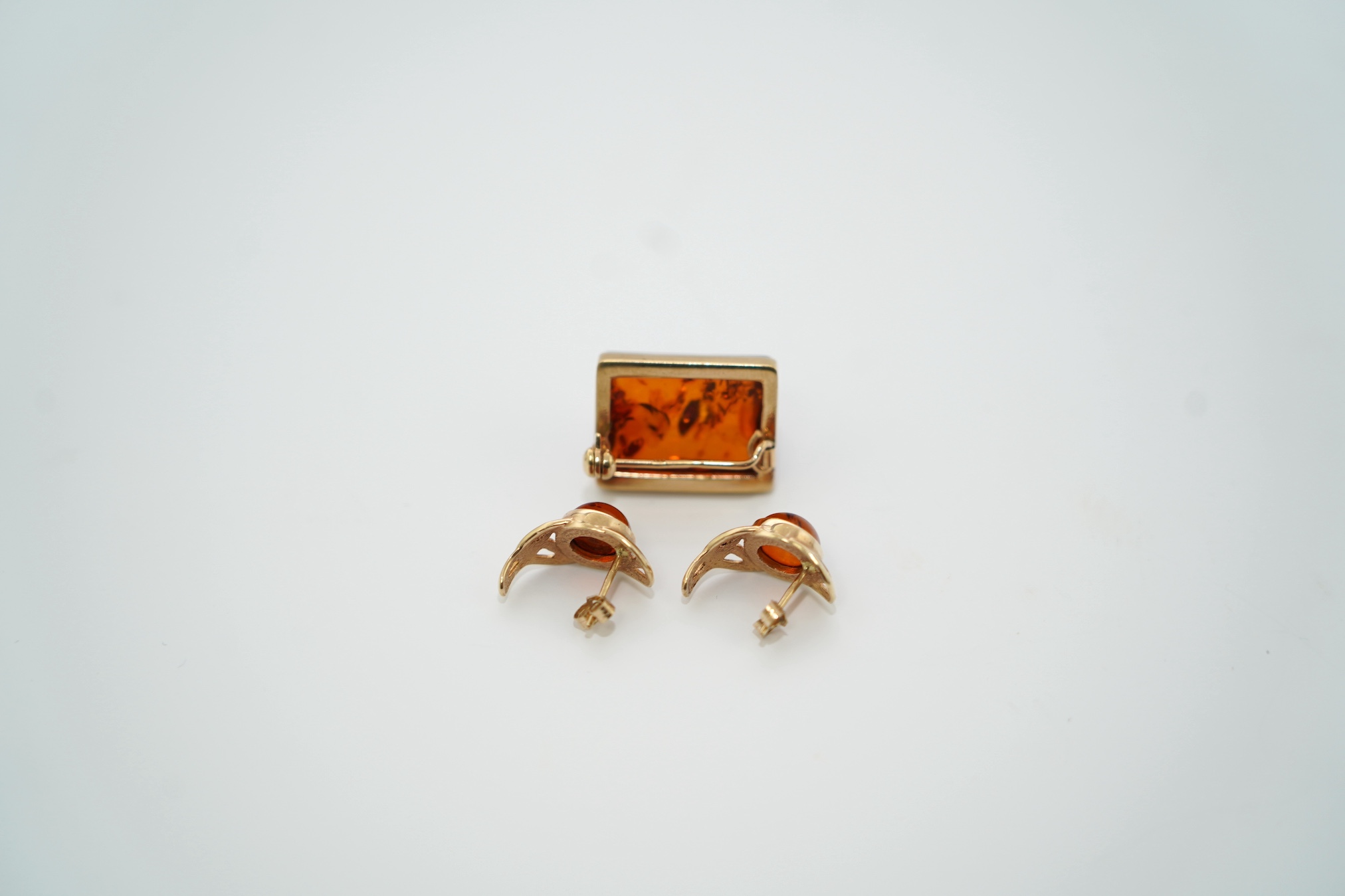 A modern pair of 9ct gold and amber set earrings and a 9ct gold mounted amber brooch, 19mm, gross weight 7.3 grams. Condition - good